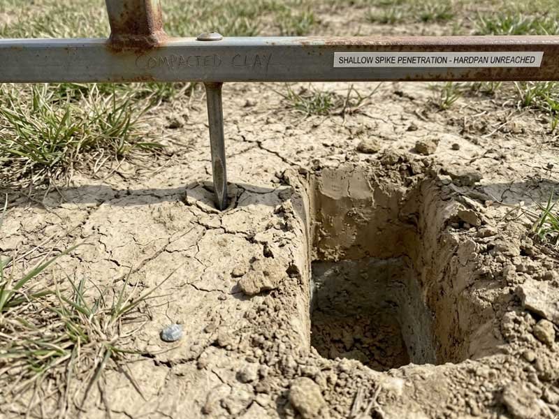 short aerator spike failing to reach clay hardpan layer close up of shallow spike penetration in compacted clay soil